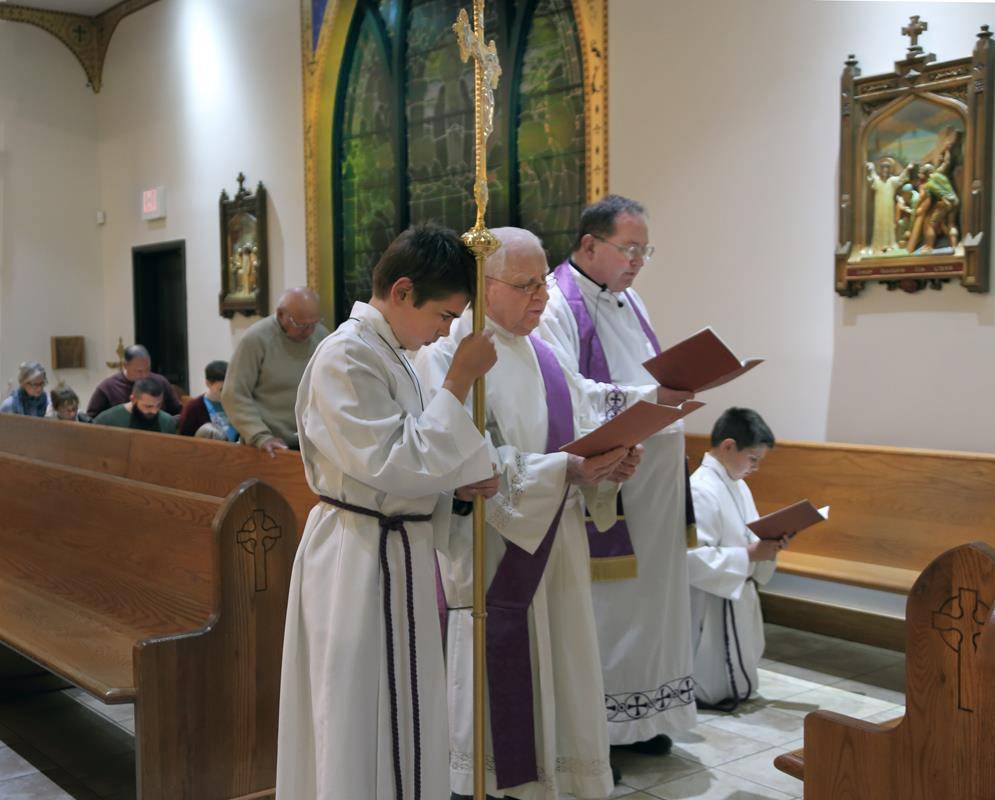 FOREST CITY — Father Herbert Burke, pastor, and Deacon Andy Cilone lead parishioners of Immaculate Conception Church in praying the Stations of the Cross March 3. Also pictured are cross bearer Maximilian Delaughter and altar server Nicholas Delaughter. (